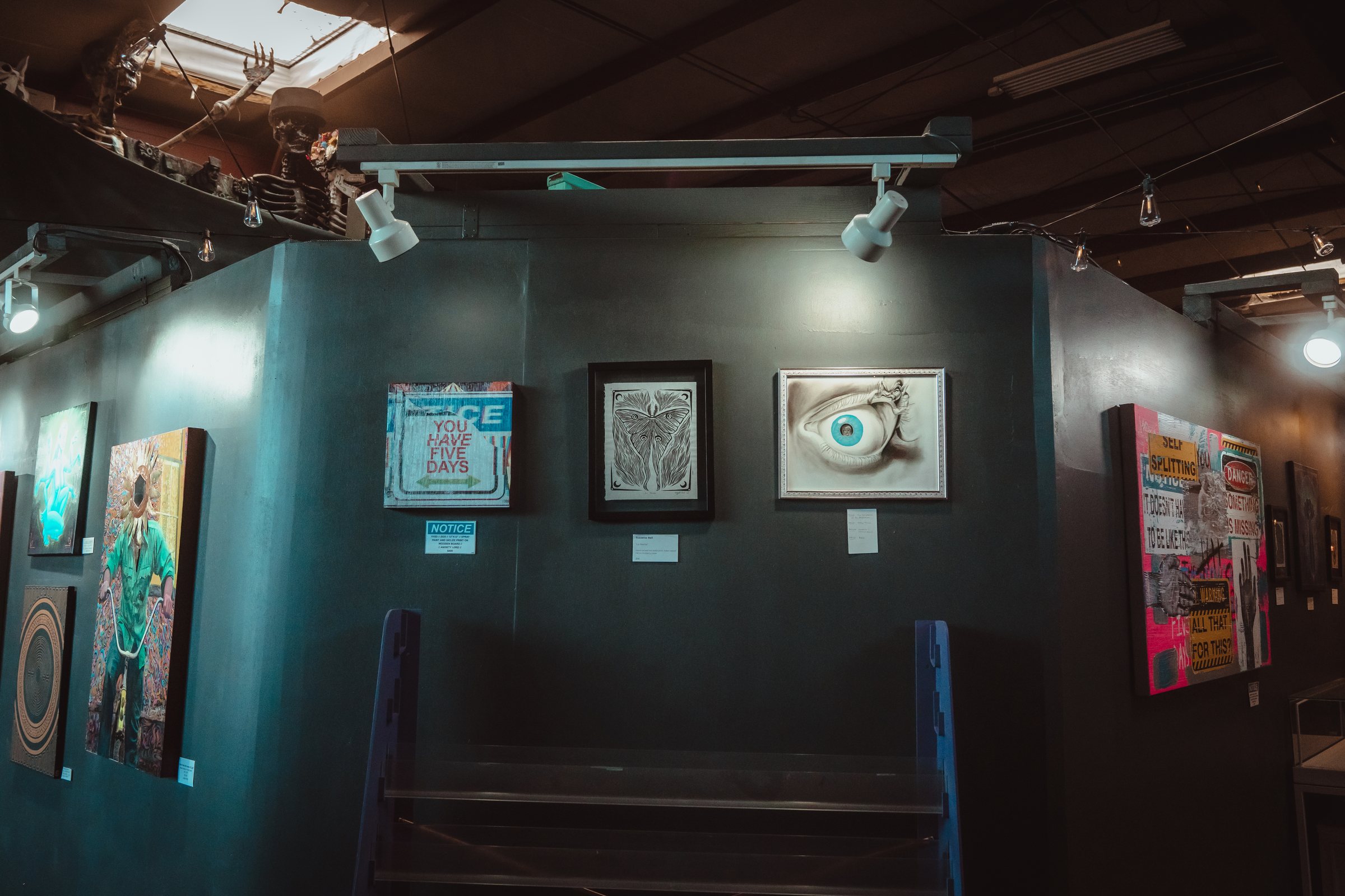 Framed paintings on the teal gallery wall