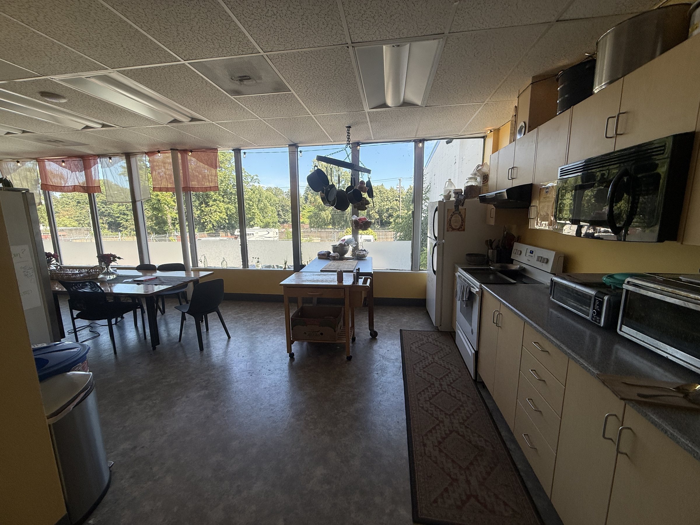 Bright communal kitchen at The Haven PDX with a long window wall, a dining table and full appliances